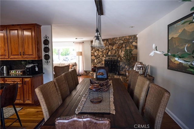 dining space with wood finished floors and a stone fireplace