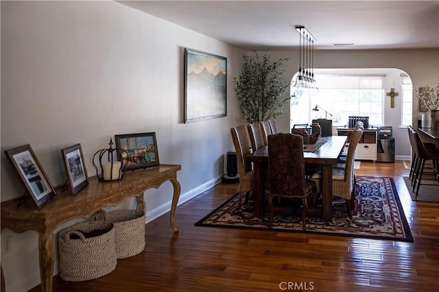 dining area with wood finished floors, baseboards, and arched walkways