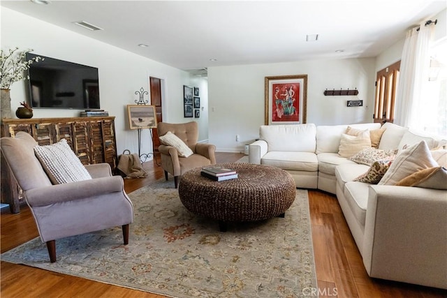 living area with visible vents and wood finished floors