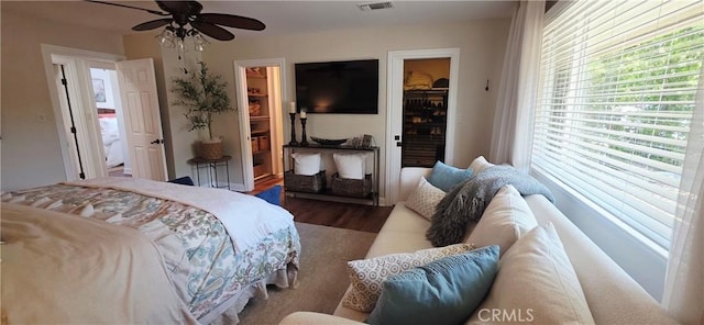 bedroom featuring visible vents, a closet, wood finished floors, a ceiling fan, and a walk in closet