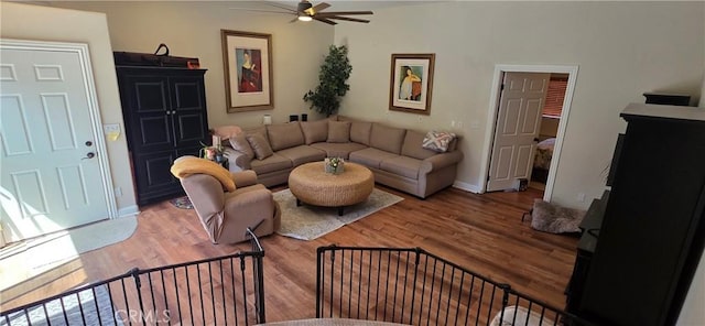 living room featuring baseboards, a ceiling fan, and light wood-style floors