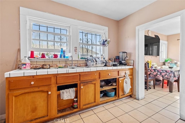 kitchen featuring light tile patterned floors, a sink, and brown cabinetry