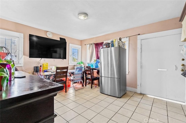 interior space with light tile patterned floors and freestanding refrigerator