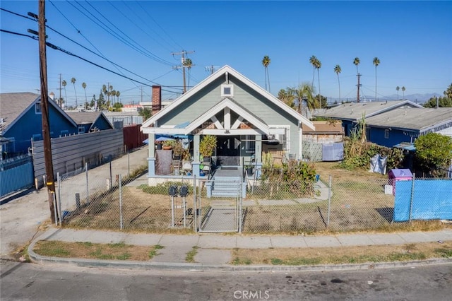 bungalow-style house featuring covered porch, a gate, and a fenced front yard