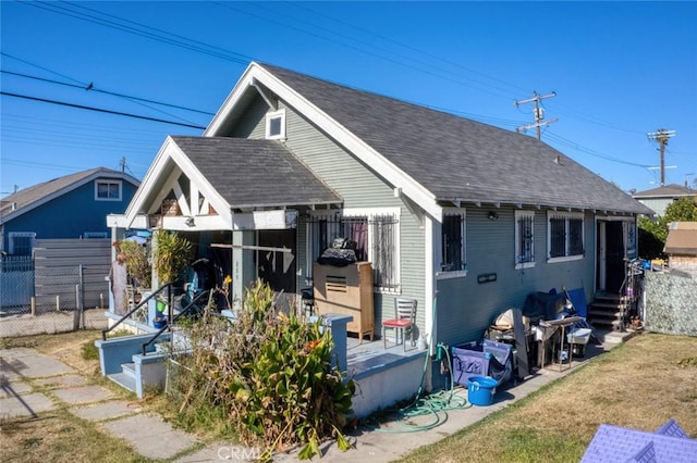 exterior space with roof with shingles, fence, and a lawn