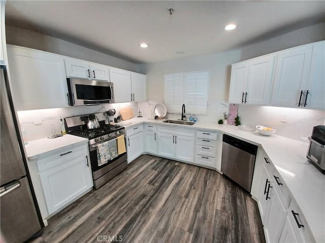 kitchen with dark wood-type flooring, light countertops, a sink, and appliances with stainless steel finishes
