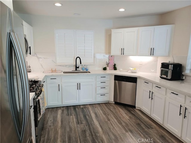 kitchen with dark wood-style flooring, light countertops, appliances with stainless steel finishes, white cabinetry, and a sink