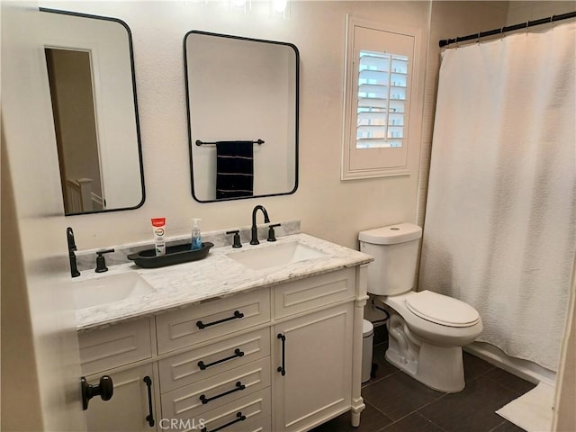 bathroom with toilet, a sink, double vanity, and tile patterned flooring
