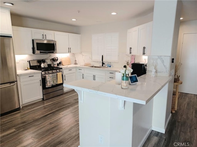 kitchen featuring decorative backsplash, a peninsula, light stone countertops, stainless steel appliances, and dark wood-style floors
