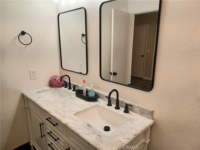 bathroom with double vanity, a sink, and a textured wall