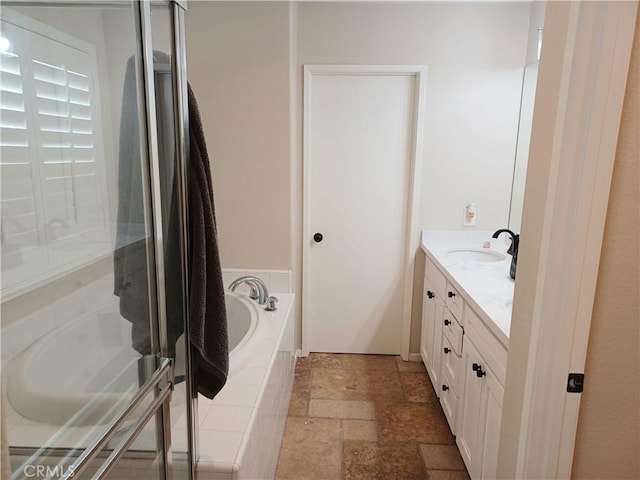 bathroom featuring vanity, a garden tub, a stall shower, and stone tile flooring