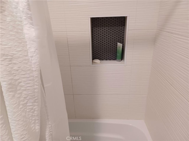 details featuring shower / bathtub combination with curtain and a textured wall