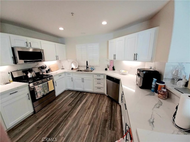 kitchen with tasteful backsplash, stainless steel appliances, dark wood-type flooring, a sink, and white cabinets