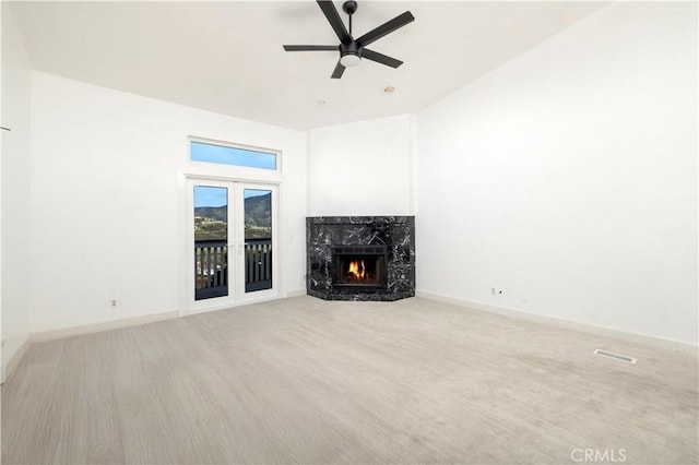 unfurnished living room with visible vents, ceiling fan, a high end fireplace, and baseboards
