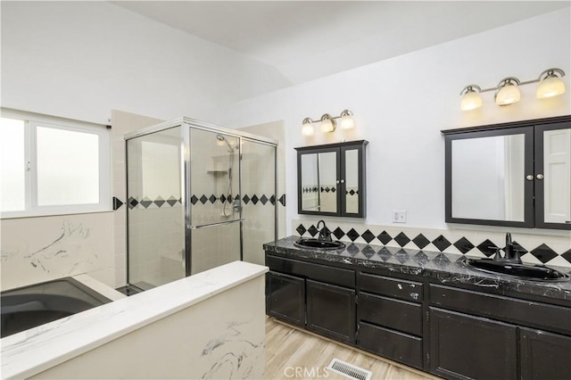 full bathroom featuring tiled shower, decorative backsplash, a sink, and visible vents
