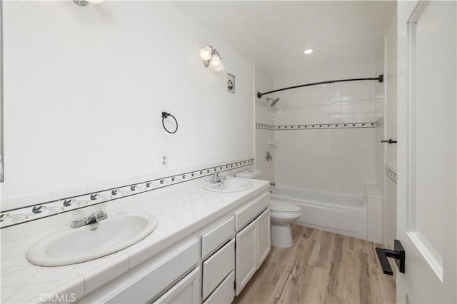 bathroom featuring double vanity, a sink, toilet, and wood finished floors