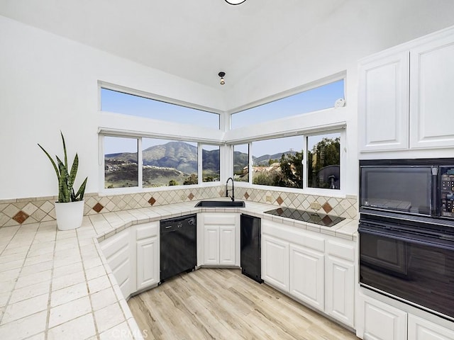 kitchen with tasteful backsplash, tile countertops, a sink, and black appliances