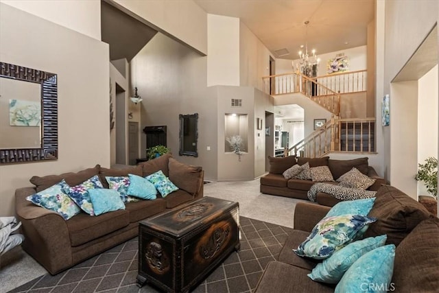 carpeted living room with a towering ceiling, visible vents, a chandelier, and stairs