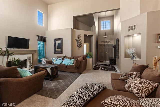 19189 San Jacinto Way, Apple Valley, CA 92308 - living room featuring a glass covered fireplace, dark colored carpet, visible vents, and a towering ceiling