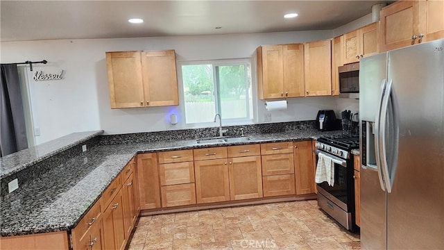 kitchen featuring recessed lighting, stainless steel appliances, dark stone countertops, a sink, and a peninsula