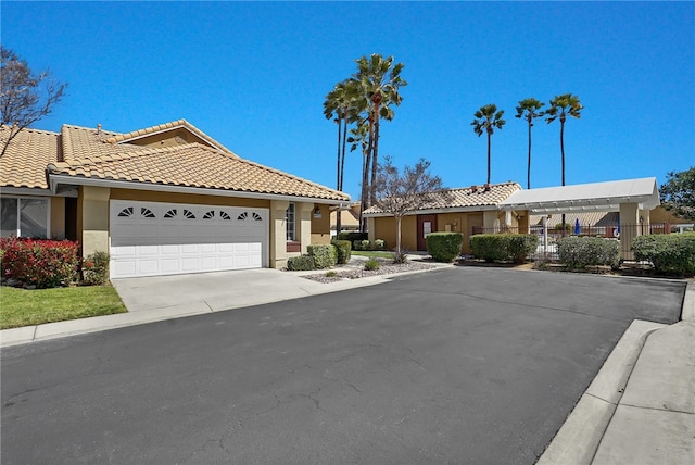 view of front of house with an attached garage, driveway, a tiled roof, and stucco siding