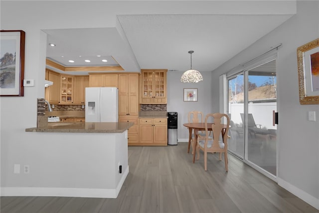 kitchen featuring tasteful backsplash, a tray ceiling, baseboards, and white fridge with ice dispenser