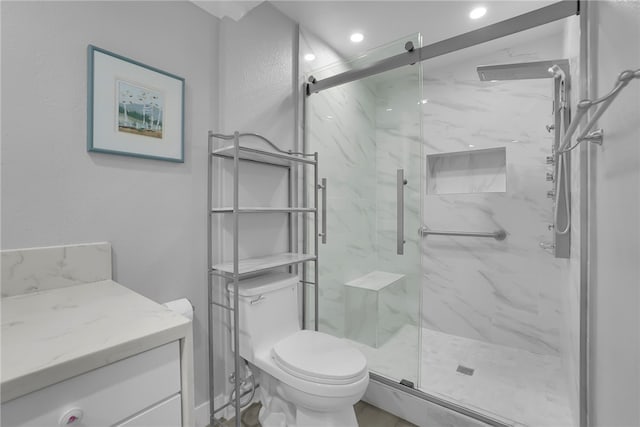 bathroom with toilet, a marble finish shower, vanity, and recessed lighting