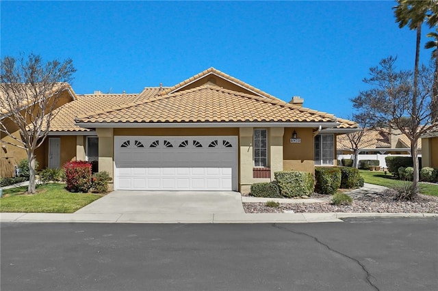 view of front of house with an attached garage, a chimney, concrete driveway, a tile roof, and stucco siding