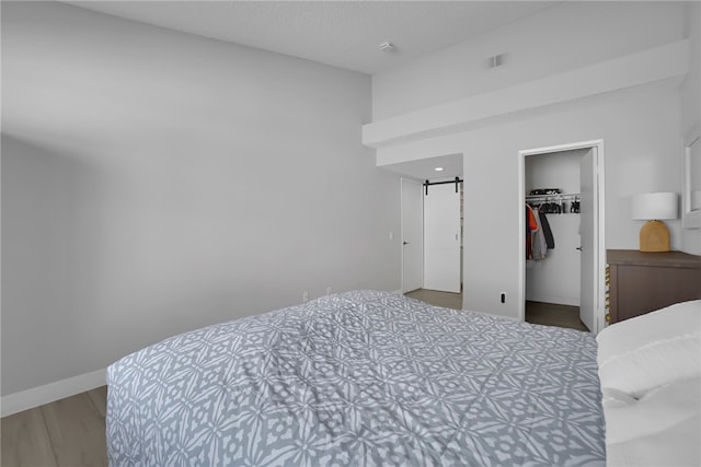 bedroom featuring a spacious closet, a closet, and wood finished floors