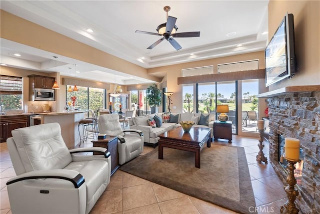 9 Via Haciendas, Rancho Mirage, CA 92270 - living room featuring a raised ceiling, light tile patterned flooring, a fireplace, and a ceiling fan