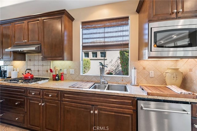 9 Via Haciendas, Rancho Mirage, CA 92270 - kitchen featuring light stone counters, appliances with stainless steel finishes, a sink, under cabinet range hood, and backsplash