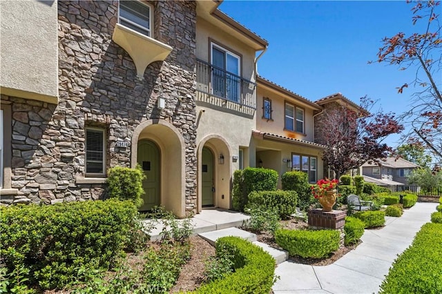 28476 Herrera St, Valencia, CA 91354 - property entrance featuring stone siding, a balcony, and stucco siding