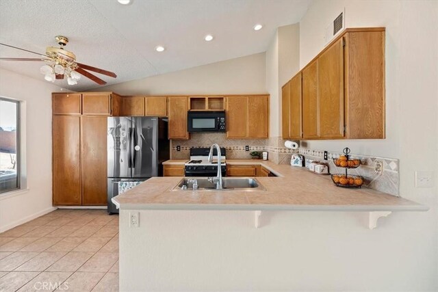 12963 Birch Glen Ct, Victorville, CA 92392 - kitchen with black microwave, freestanding refrigerator, a peninsula, a sink, and light countertops