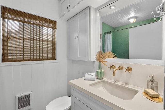 full bath with heating unit, a shower with shower curtain, toilet, and vanity