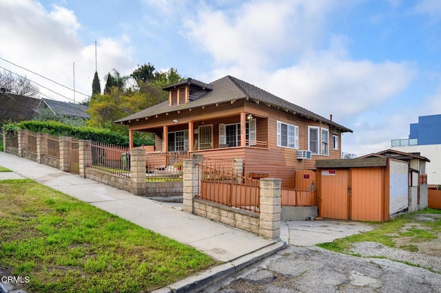 view of front of home featuring an outbuilding, a shingled roof, fence, and a storage shed