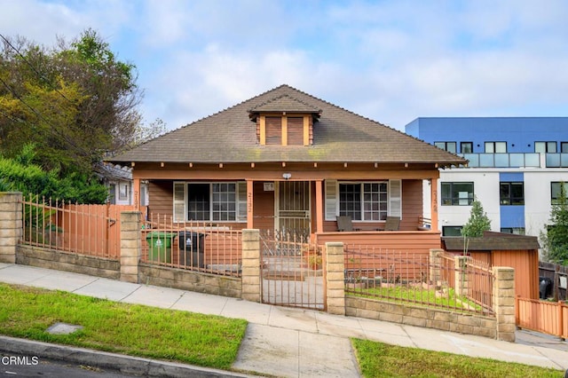 bungalow-style house featuring a porch, a gate, a fenced front yard, and a shingled roof