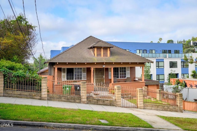 bungalow-style house with a fenced front yard, covered porch, and a gate