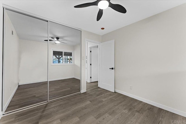 unfurnished bedroom featuring baseboards, wood finished floors, ceiling fan, and a closet