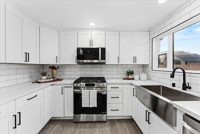 kitchen featuring white cabinets, stainless steel appliances, backsplash, and a sink