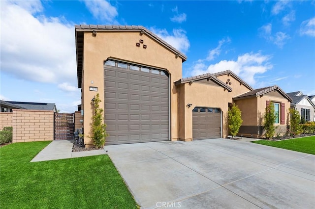 mediterranean / spanish-style house with a front yard, a garage, concrete driveway, stucco siding, and a gate