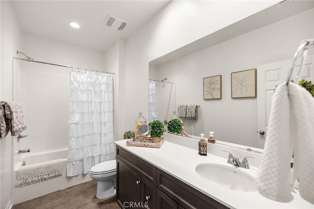 bathroom featuring vanity, toilet, visible vents, shower / bath combo with shower curtain, and wood finished floors