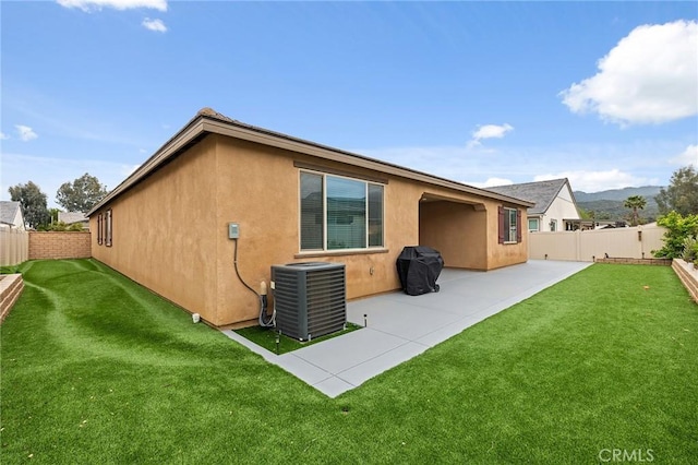 rear view of house with a fenced backyard, cooling unit, a lawn, and stucco siding