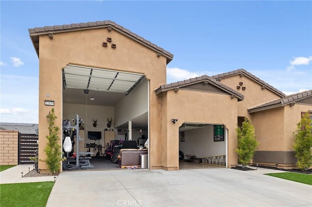 rear view of property featuring a tiled roof, stucco siding, a patio area, an attached garage, and driveway