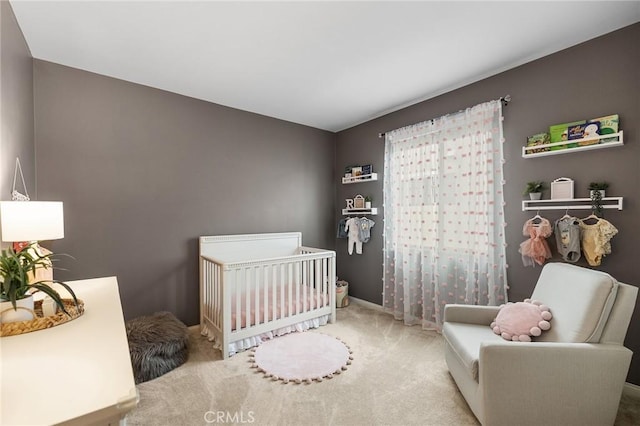 carpeted bedroom featuring baseboards and a nursery area