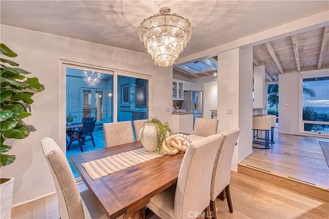 dining area featuring baseboards, a notable chandelier, beam ceiling, and light wood-type flooring