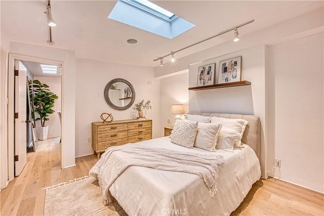bedroom featuring a skylight, track lighting, and light wood-type flooring