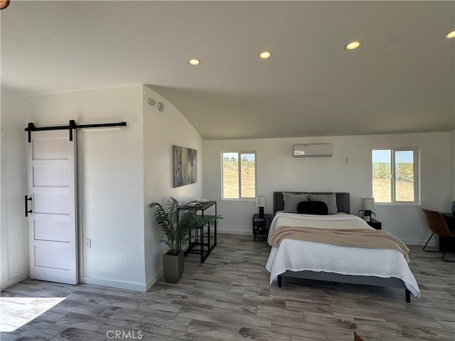 bedroom with multiple windows, vaulted ceiling, a wall unit AC, and a barn door