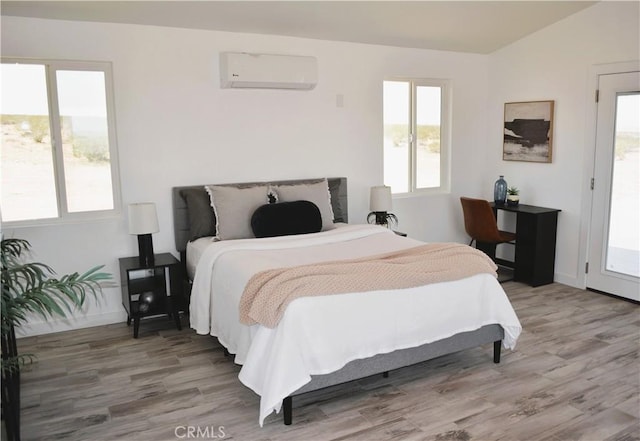 bedroom with wood finished floors, a wall unit AC, and multiple windows