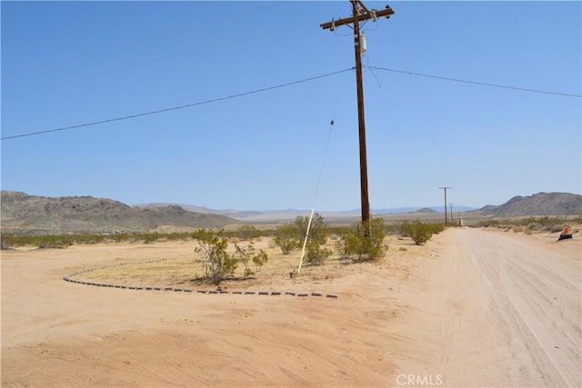 view of road with a rural view and a mountain view