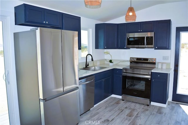 kitchen with light countertops, vaulted ceiling, blue cabinets, a sink, and appliances with stainless steel finishes